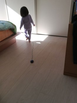 Bambina a piedi scalzi in camera da letto, gioca da sola trascinando un mouse a terra