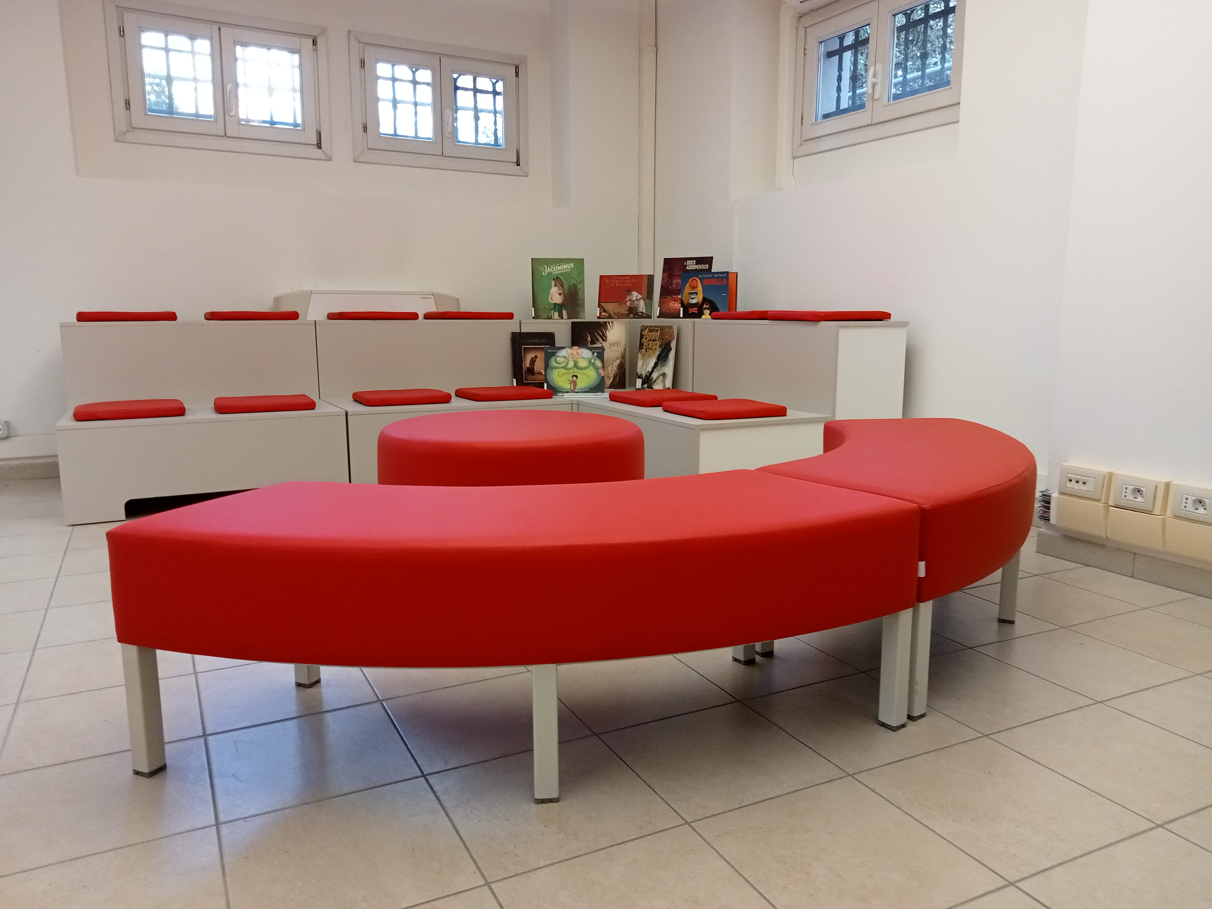 Albi illlustrati, tribuna e divanetti in zona lettura e drammatizzazione